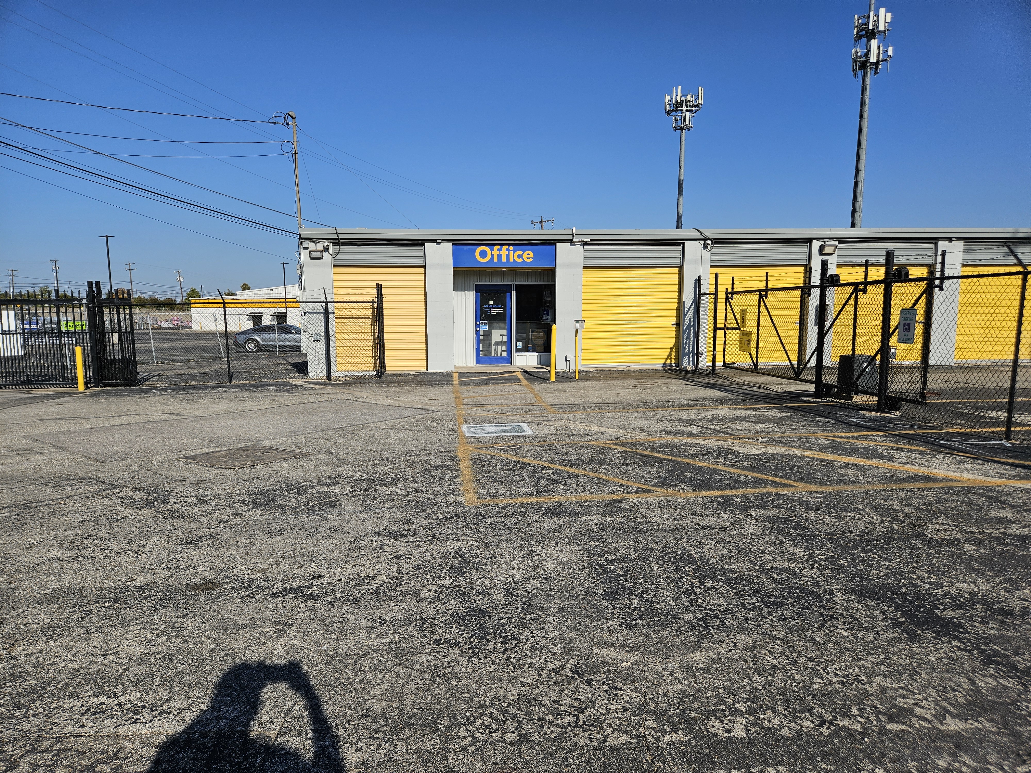 Entrance and office of Round Rock Secure Storage with yellow roll-up units and secure gate under clear blue sky near Hutto, TX.